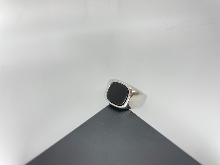 Silver ring with a black stone on a gray surface
