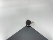 Silver ring with a black stone on a gray surface